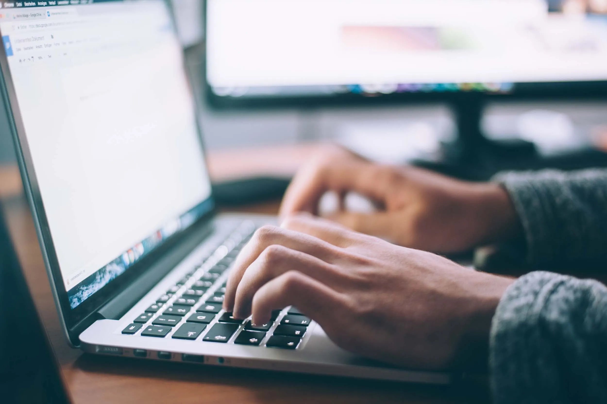 persona che scrive su una tastiera di un pc portatile